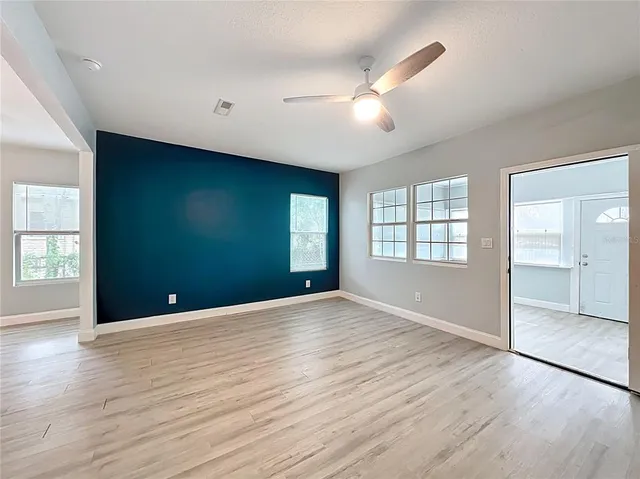 an empty room with wooden floor and windows