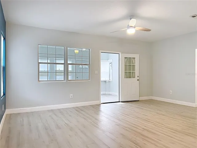 a view of an empty room with wooden floor and a bathroom