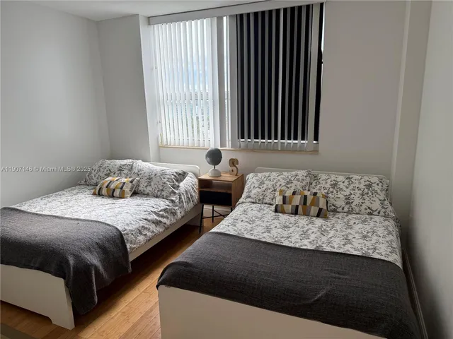 a bedroom with two beds and a large window