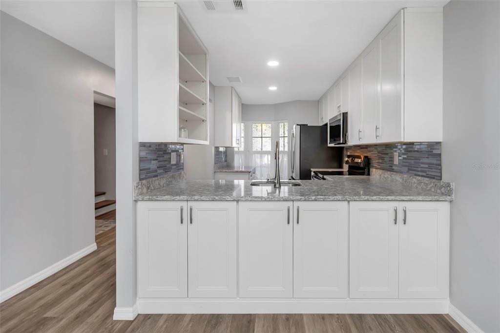 6520 Thicket Trail New Port Richey, FL 34653 - Photo 12 of 43 a kitchen with granite countertop white cabinets and stainless steel appliances