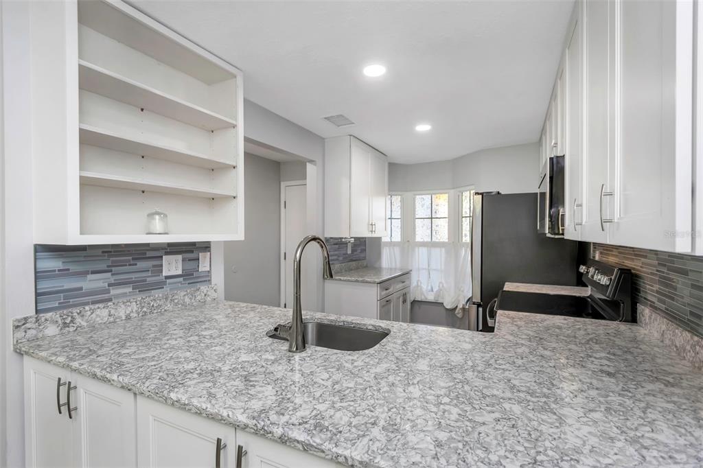 6520 Thicket Trail New Port Richey, FL 34653 - Photo 14 of 43 a kitchen with stainless steel appliances granite countertop a sink and a refrigerator