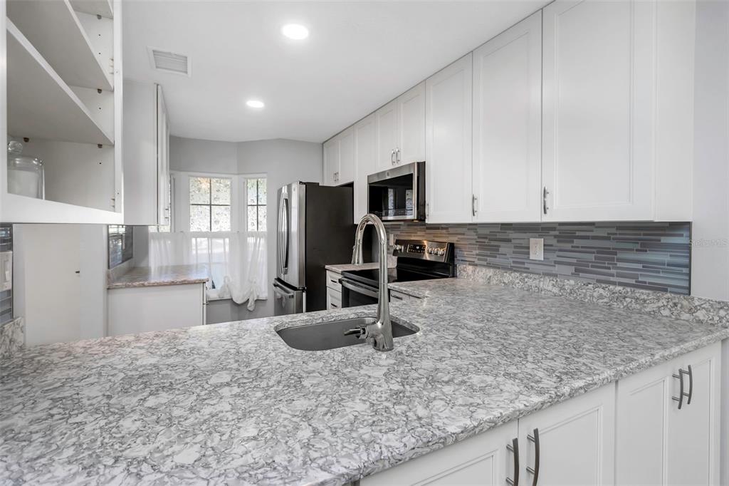 6520 Thicket Trail New Port Richey, FL 34653 - Photo 15 of 43 a kitchen with stainless steel appliances granite countertop a sink a stove and a microwave