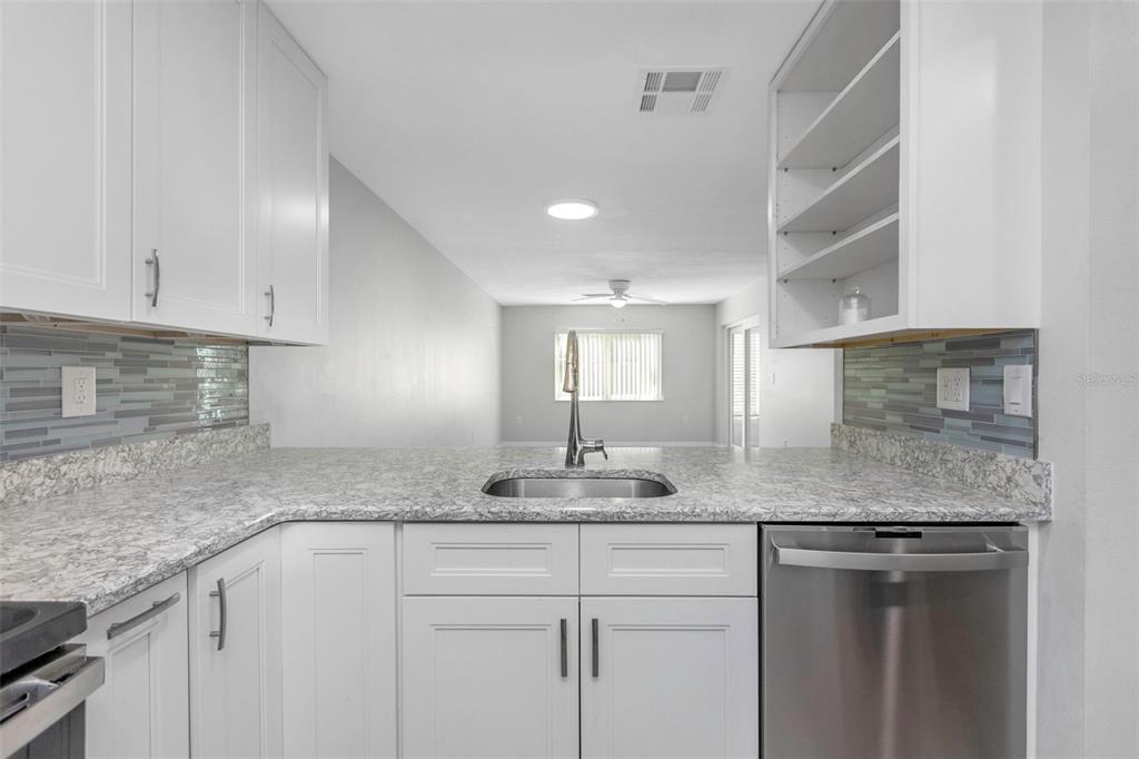 6520 Thicket Trail New Port Richey, FL 34653 - Photo 16 of 43 a kitchen with granite countertop a sink and white cabinets