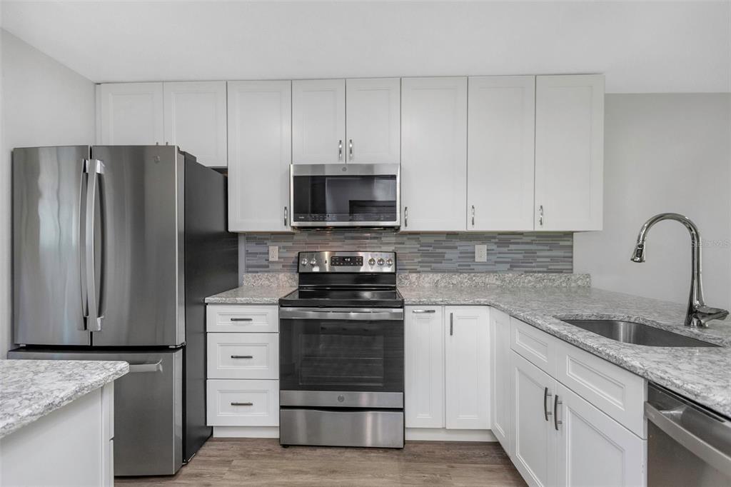 6520 Thicket Trail New Port Richey, FL 34653 - Photo 18 of 43 a kitchen with granite countertop white cabinets and stainless steel appliances