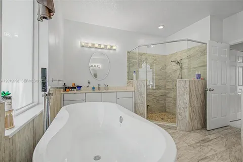 a spacious bathroom with a tub sink mirror and shower
