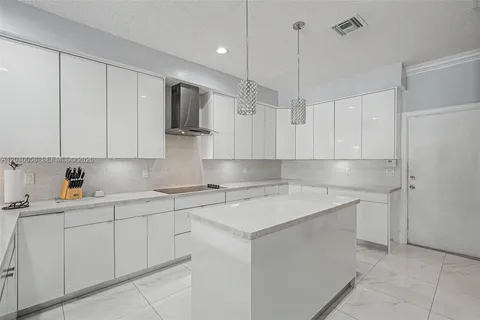 a kitchen with a sink dishwasher and white cabinets with wooden floor