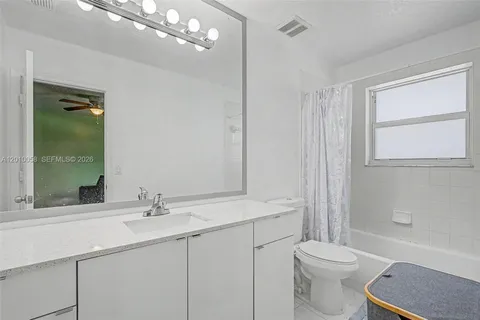 a bathroom with a toilet a sink a mirror a vanity and window