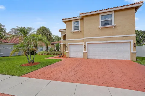 front view of house with a yard and palm trees