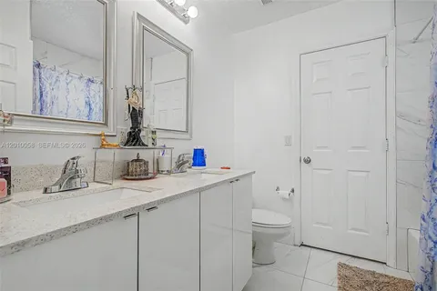 a bathroom with a granite countertop sink a toilet and a mirror