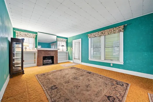 a view of an empty room with a fireplace and a window