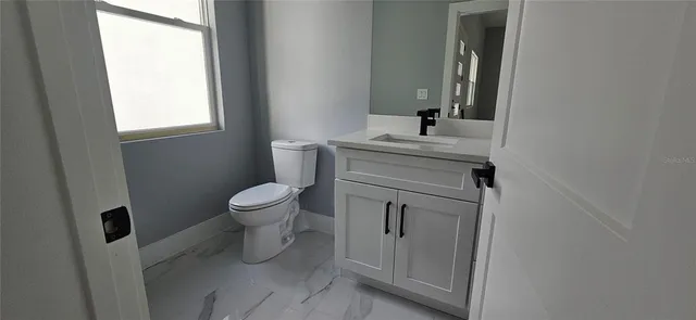 a bathroom with a toilet a sink a window and mirror