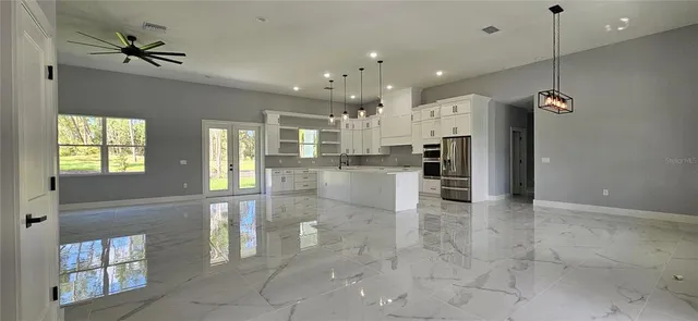 a view of large kitchen with kitchen island granite countertop refrigerator and sink