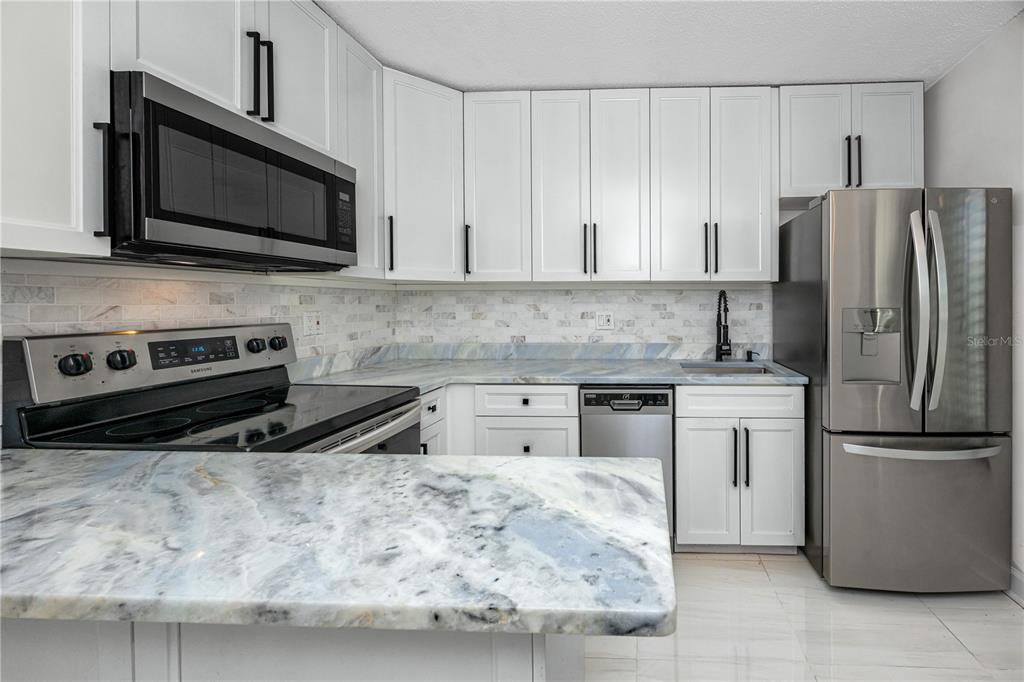 2207 Belleair Road, Unit B4 Clearwater, FL 33764 - Photo 5 of 37 a kitchen with stainless steel appliances granite countertop a stove microwave and refrigerator
