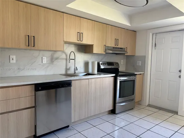 a view of a refrigerator in kitchen and an empty room in wooden floor