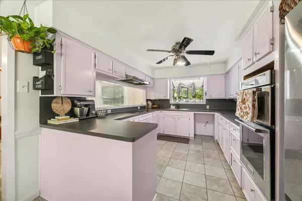 a large kitchen with a sink a counter top space stainless steel appliances and a window