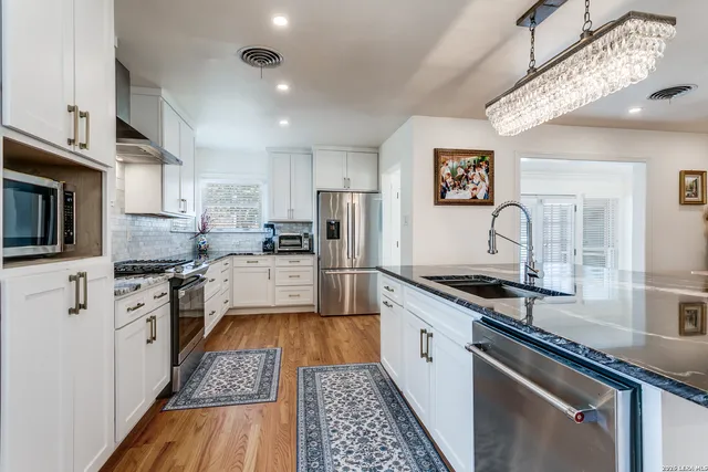 a large kitchen with stainless steel appliances granite countertop a stove refrigerator and a microwave