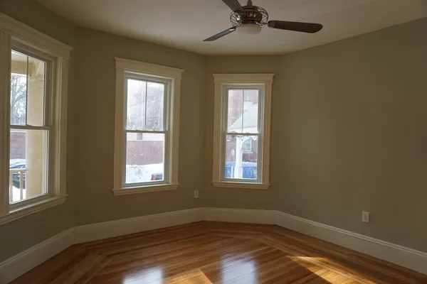 a view of an empty room with wooden floor and a window