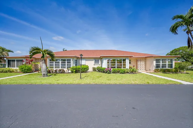 a view of yellow house with a big yard and large trees