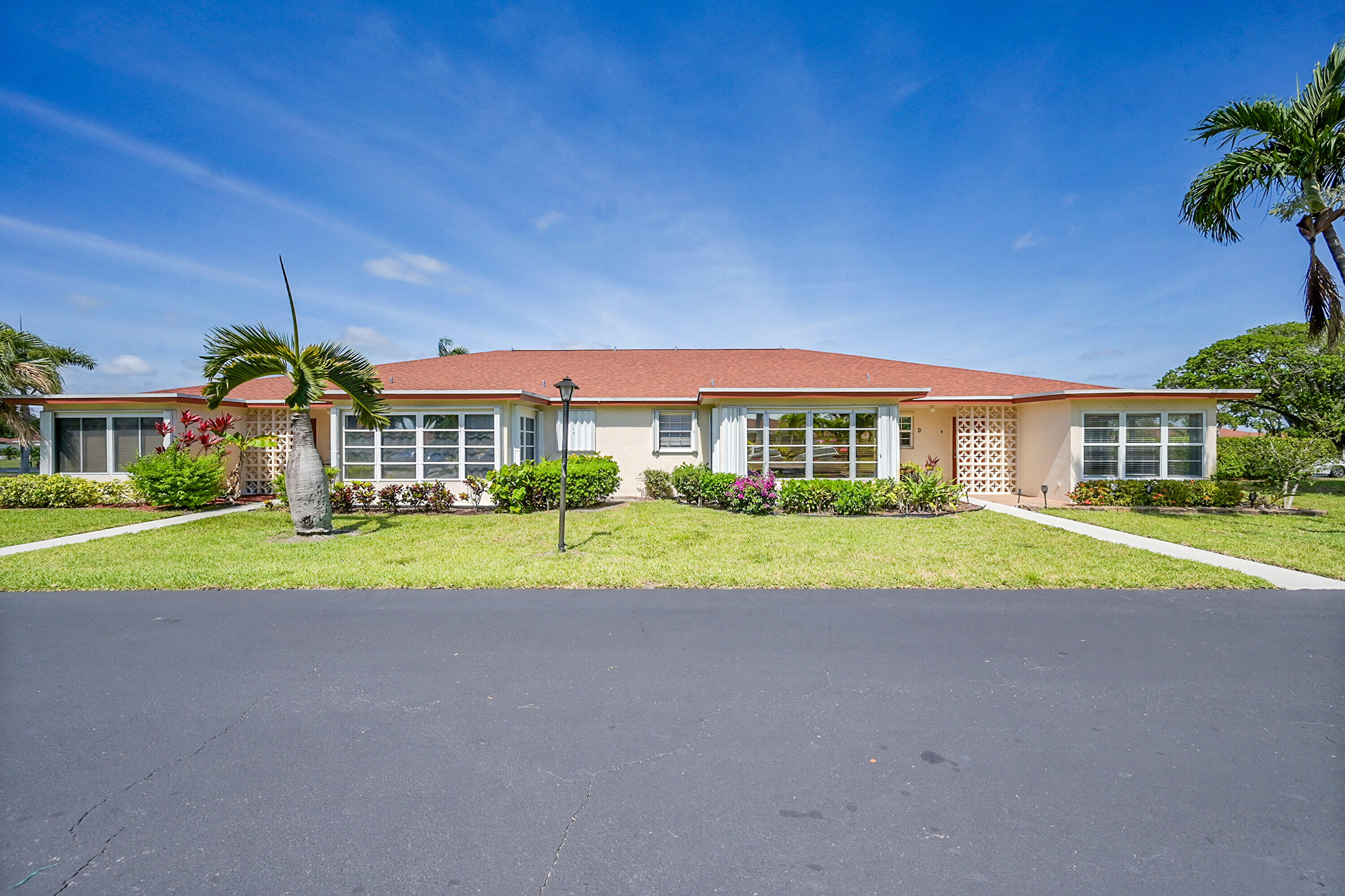 4585 Northwest 3rd Street, Unit D Delray Beach, FL 33445 - Photo 2 of 45 a view of yellow house with a big yard and large trees