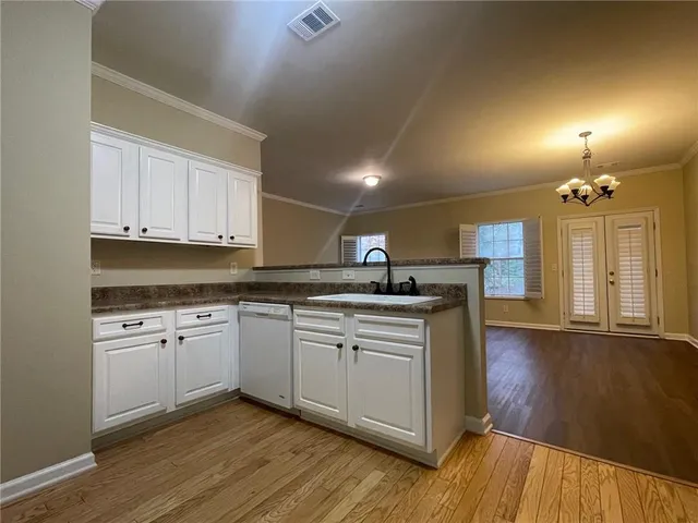 a kitchen with stainless steel appliances granite countertop a sink a stove a refrigerator and white cabinets with wooden floor