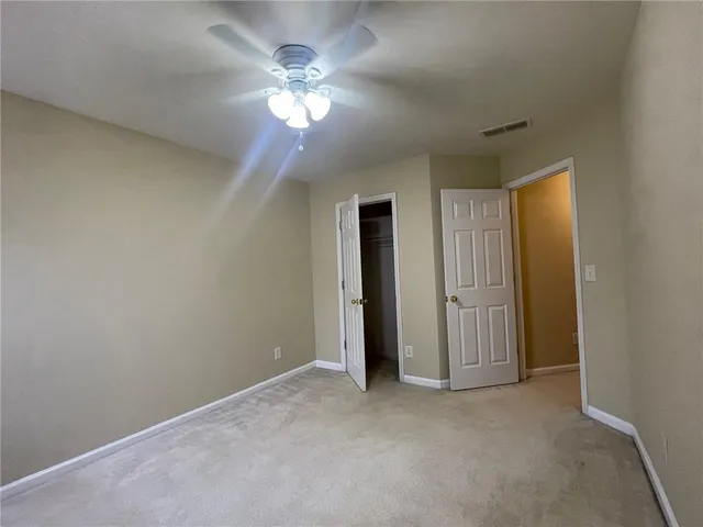an empty room with a chandelier fan and windows