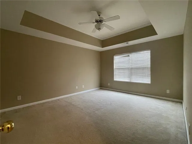 an empty room with a chandelier fan and windows