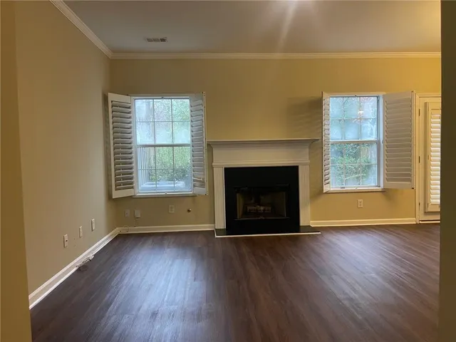 an empty room with wooden floor a fireplace and windows