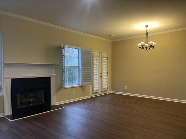 a view of an empty room with wooden floor fireplace and a window