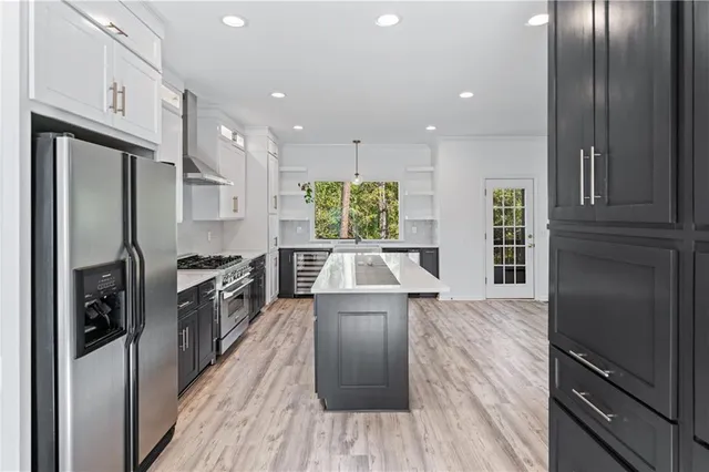 a kitchen with stainless steel appliances granite countertop a refrigerator a stove and a wooden floors