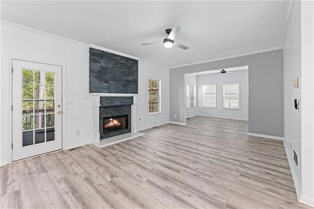 a view of an empty room with wooden floor fireplace and a window
