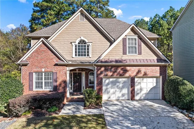 a view of a house with a yard plants and large tree