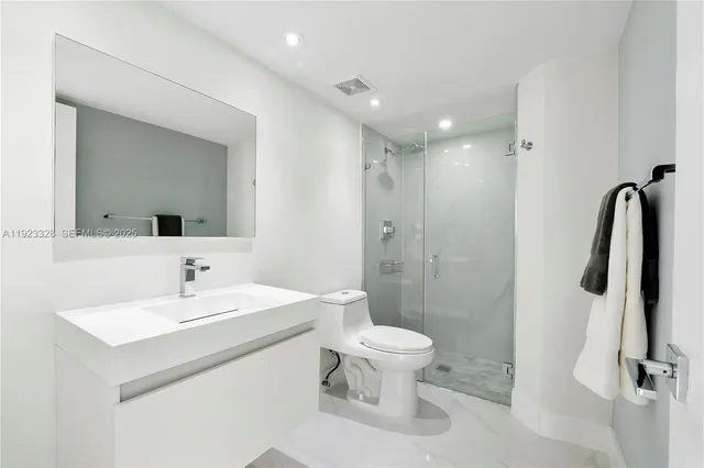 a bathroom with a toilet a sink a mirror and a shower