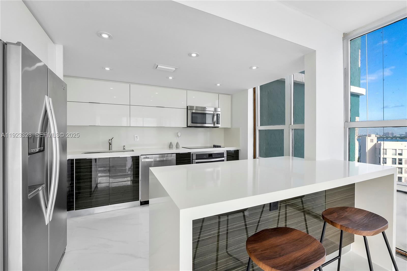 780 Northeast 69th Street, Unit 1601 Miami, FL 33138 - Photo 10 of 18 a kitchen with stainless steel appliances a refrigerator a stove a sink and chairs