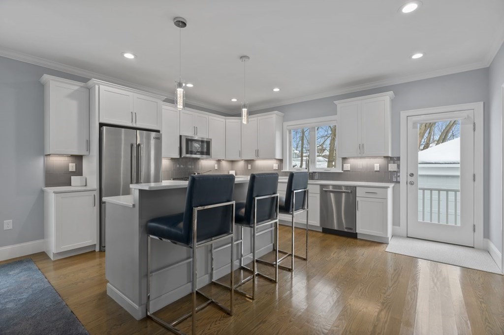 a kitchen with stainless steel appliances a refrigerator a stove top oven a sink dishwasher and a refrigerator with wooden floor