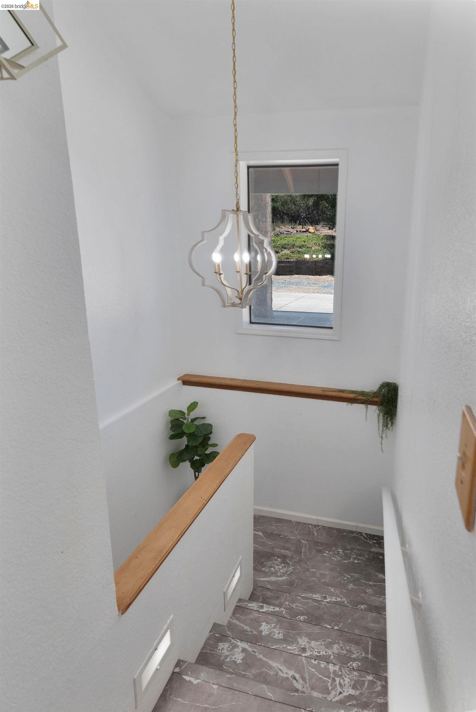 22963 Robertson Ranch Road Sonora, CA 95370 - Photo 32 of 90 Staircase featuring wood-finish handrails, integrated stair lighting, a modern hanging light fixture, and marble-look flooring