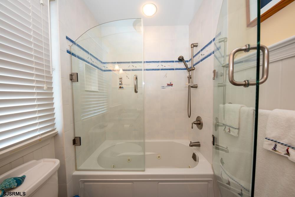 336 West Surf Road Ocean City, NJ 08226 - Photo 10 of 29 a bathroom with a shower and white bath tub sitting next to a window