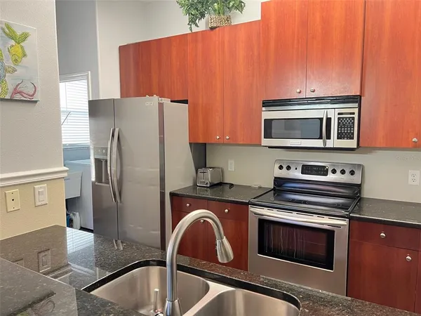 a kitchen with stainless steel appliances granite countertop a refrigerator stove top oven with a sink and dishwasher