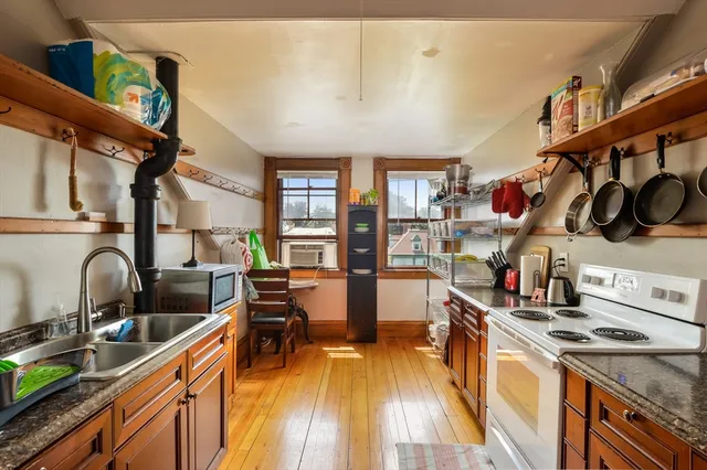 a kitchen with stainless steel appliances granite countertop a stove a sink dishwasher and cabinets with wooden floor