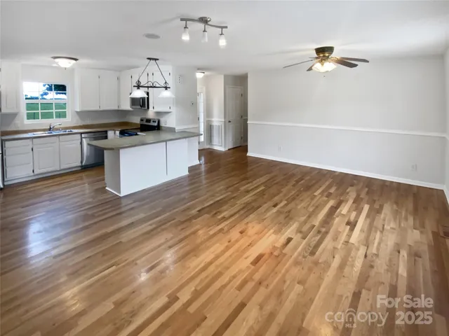 a large kitchen with kitchen island a sink dishwasher a stove and white cabinets with wooden floor