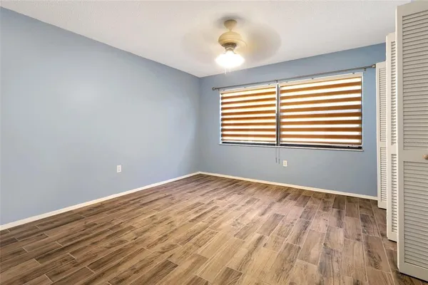a view of an empty room with wooden floor and a window