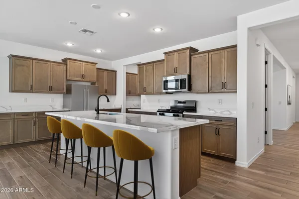 a kitchen with stainless steel appliances granite countertop a sink a stove a refrigerator cabinets and chairs