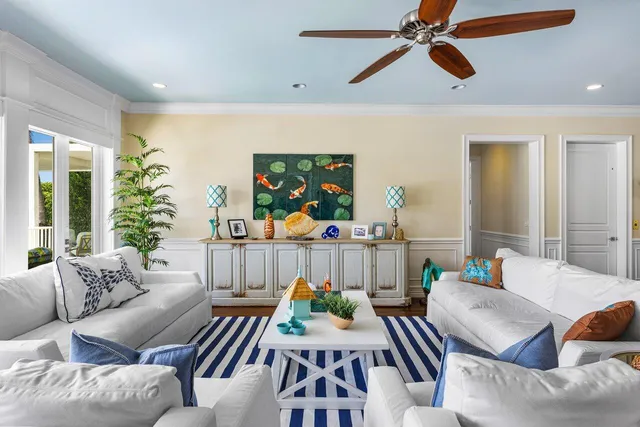 a view of a dining room and livingroom with furniture wooden floor a rug a painting and a chandelier
