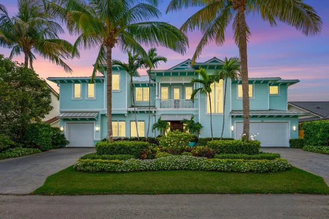 a front view of house with small garden and palm trees