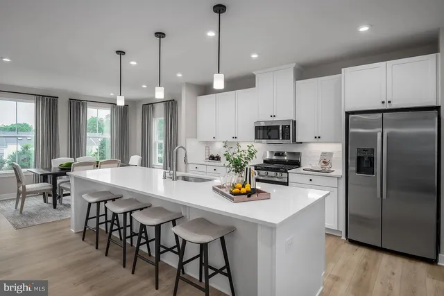 a kitchen with stainless steel appliances a dining table chairs refrigerator and microwave