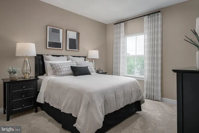 a bedroom with a bed and a lamp on dresser