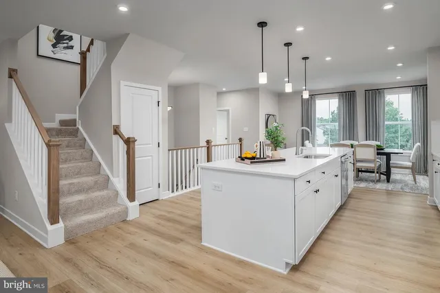 a large white kitchen with a large counter top a sink a window and stainless steel appliances