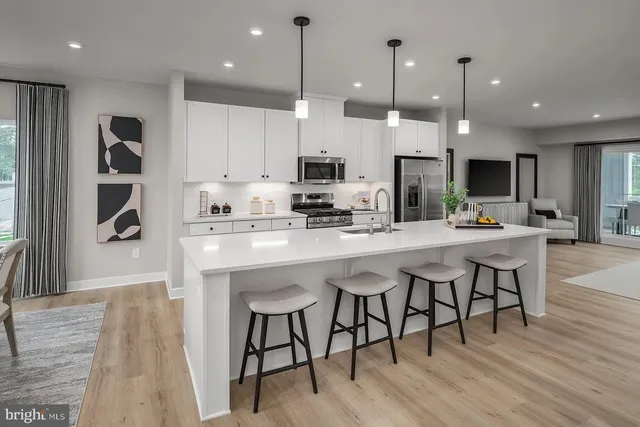 a kitchen with stainless steel appliances kitchen island granite countertop a table chairs sink and cabinets