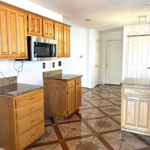a kitchen with granite countertop a stove top oven microwave and cabinets