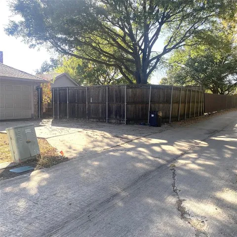 a view of a backyard with large tree and wooden fence