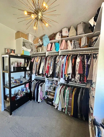 838 East Mountain Road North Ogden, UT 84414 - Photo 23 of 37 Custom closet system featuring extensive shelving and hanging rods, built-in black display unit, and carpet flooring, all illuminated by a contemporary sputnik chandelier